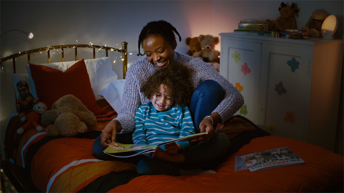 Mother and child reading together at bedtime in a darkened room with nightlights
