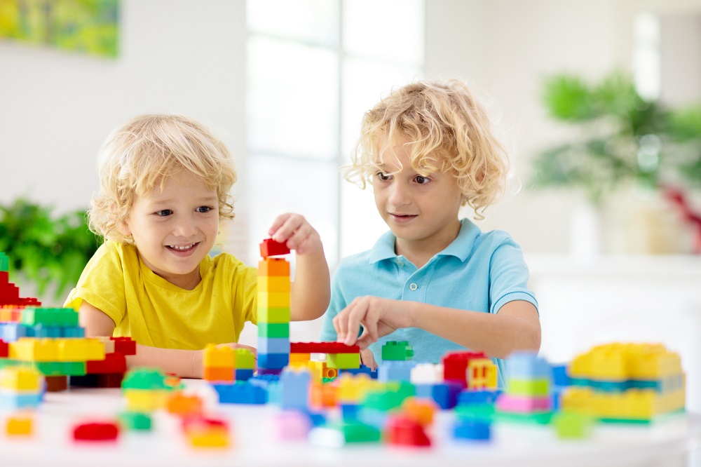 Young twin boys playing with building blocks at nursery