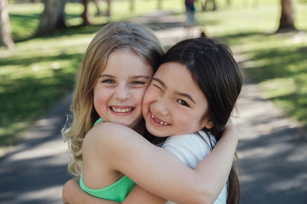 Little girls hugging each other in a park
