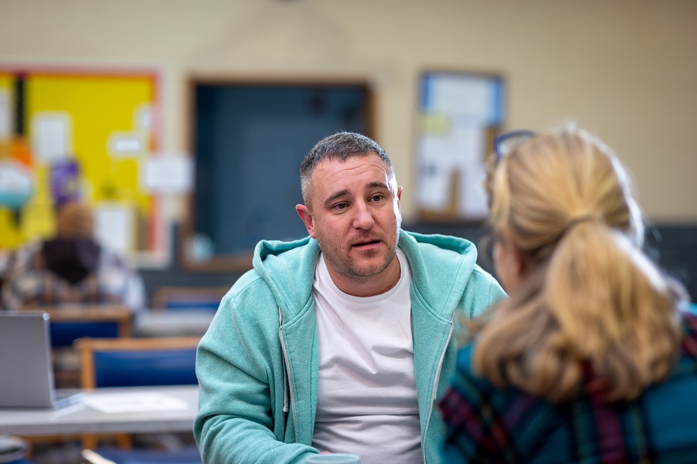 Concerned father talking to a teacher in a school classroom