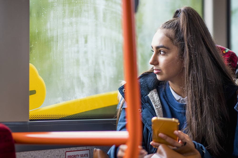 Teen girl on a bus holding her mobile phone