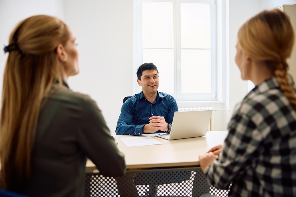 Mother and teenage girl talking to a teacher at school