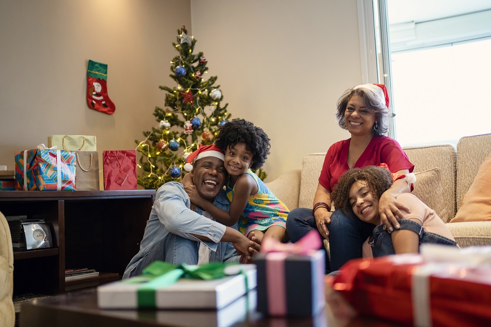 Happy family with teen and younger daughter sitting in front of a Christmas tree