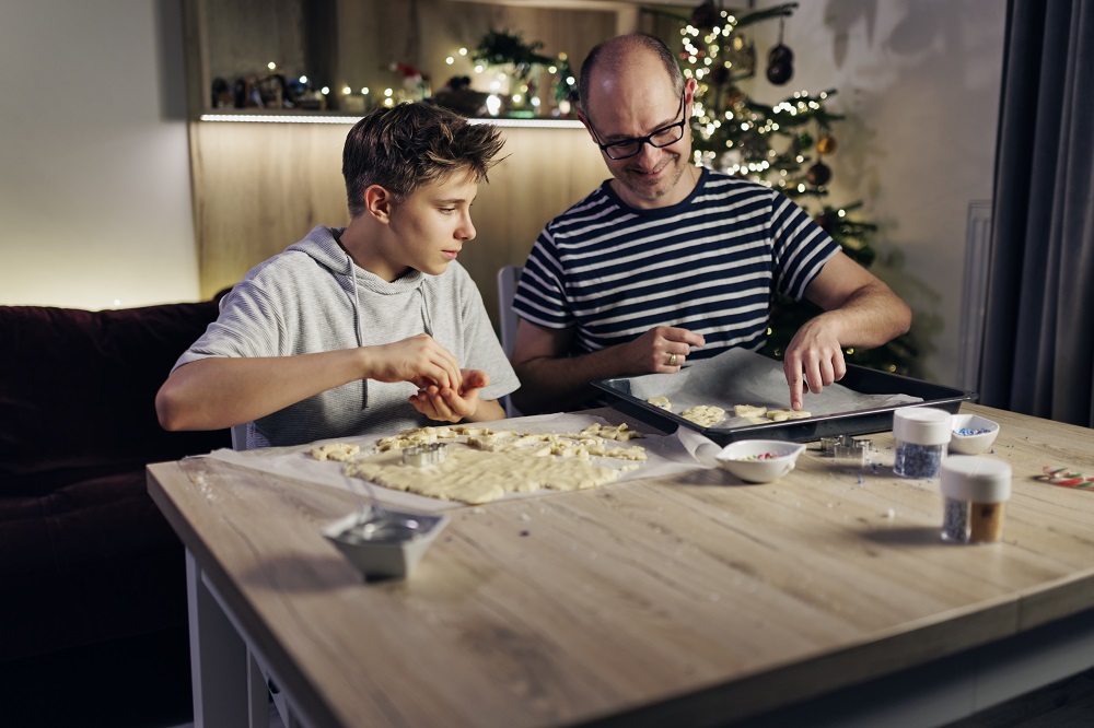 Teen boy baking Christmas cookies with his dad