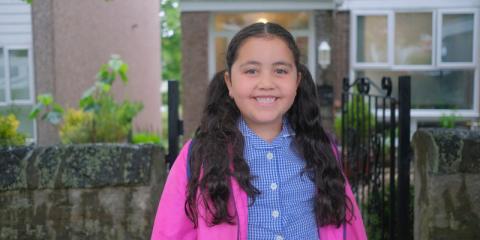 Young girl standing in front of house